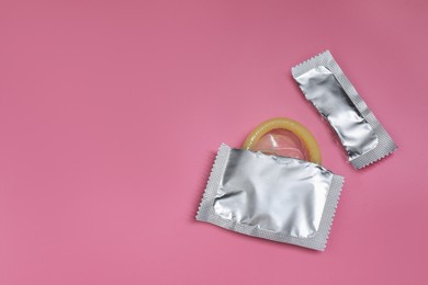 Torn condom package on pink background, space for text. Safe sex