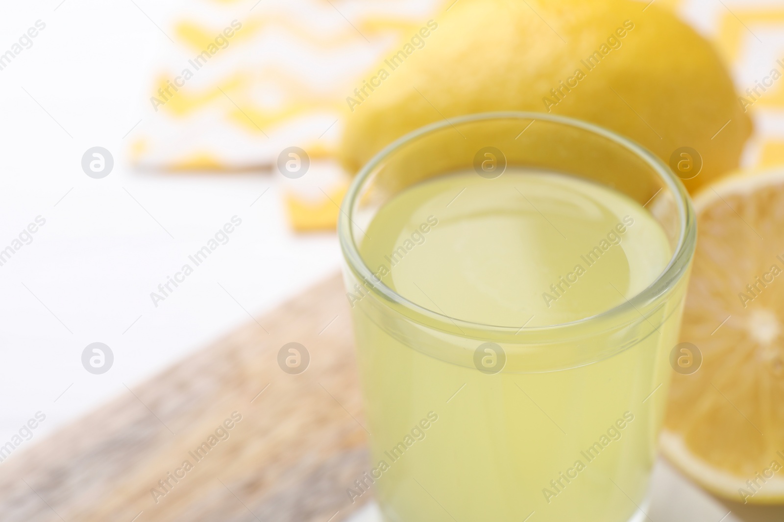 Photo of Shot glass with tasty limoncello liqueur on table, closeup. Space for text