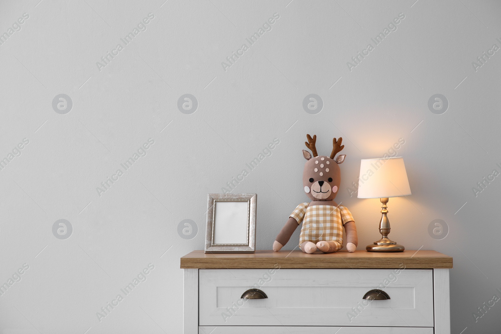 Photo of Modern white chest of drawers near light wall in child room, space for text. Interior design