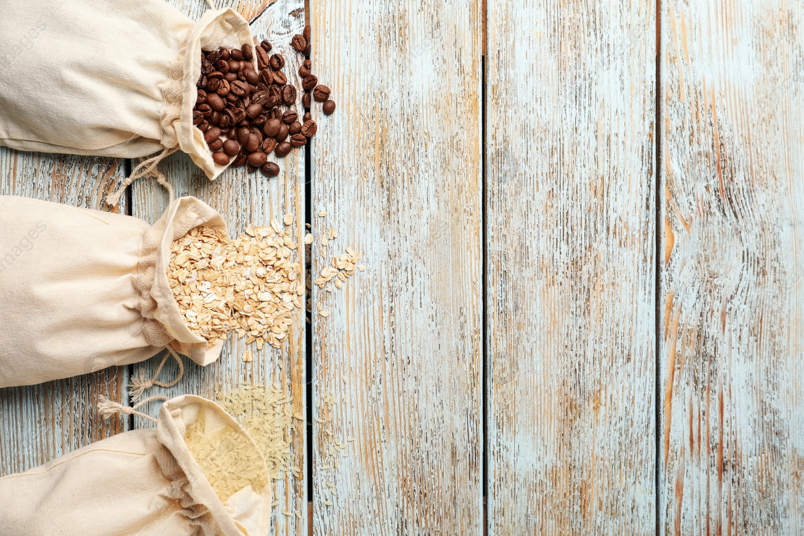 Photo of Cotton eco bags with cereals and coffee beans on wooden table, flat lay. Space for text