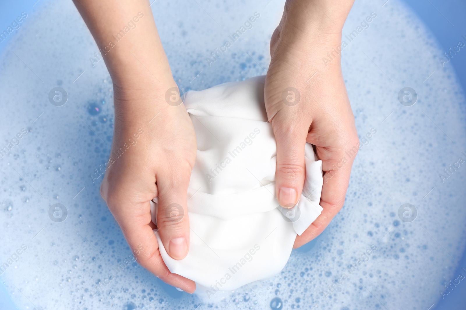 Photo of Top view of woman hand washing white clothing in suds, closeup