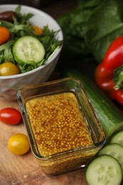 Photo of Tasty vinegar based sauce (Vinaigrette) in bowl and products on wooden table, above view