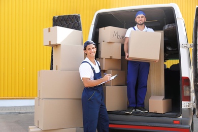 Male movers unloading boxes from van outdoors