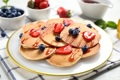 Photo of Delicious pancakes with fresh berries and syrup on light table