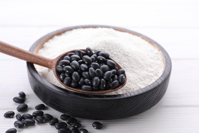 Photo of Kidney bean flour and black seeds on white wooden table, closeup