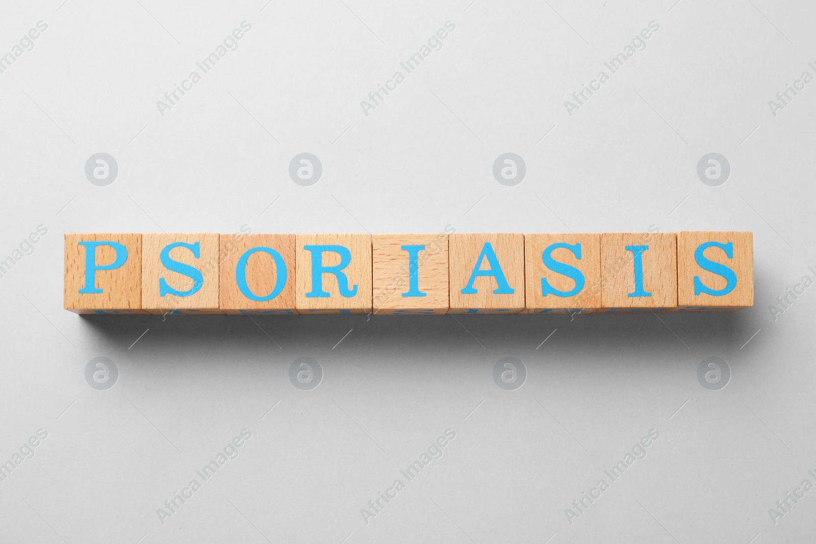Photo of Word Psoriasis made of wooden cubes with letters on light grey background, top view