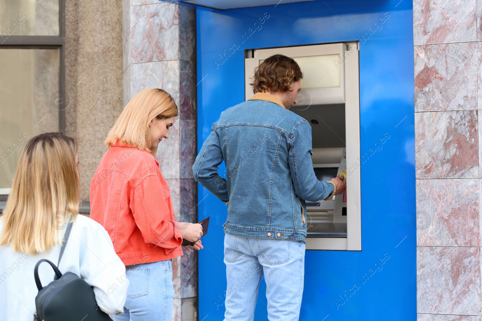 Photo of People standing in queue to cash machine outdoors