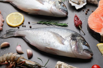Photo of Fresh raw dorado fish, salmon and oyster on grey table, closeup