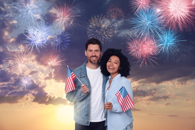 Image of 4th of July - Independence day of America. Happy couple holding national flags of United States against sky with fireworks