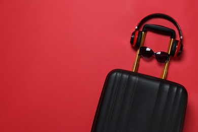 Photo of Stylish suitcase with sunglasses and headphones on color background, top view. Space for text