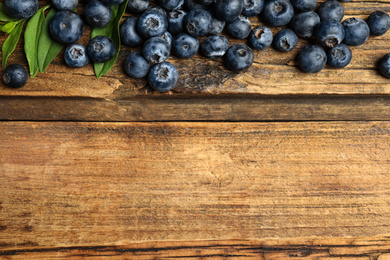 Photo of Fresh ripe blueberries on wooden table, flat lay. Space for text