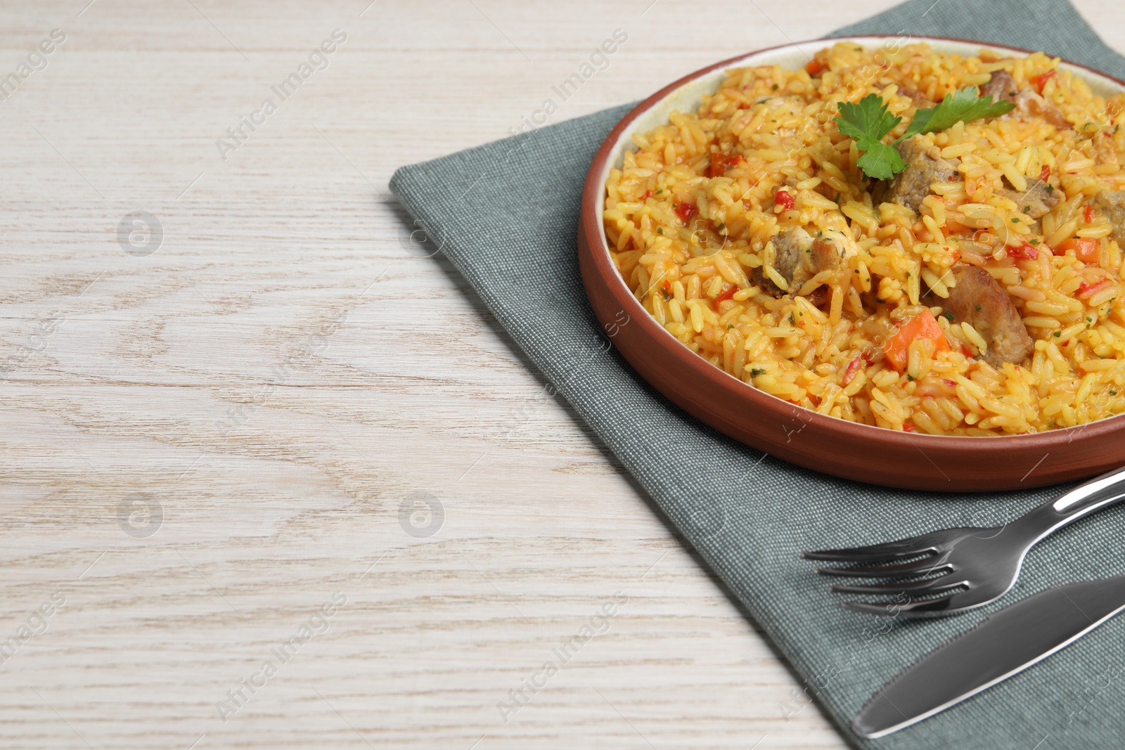 Photo of Delicious pilaf with meat served on white wooden table. Space for text