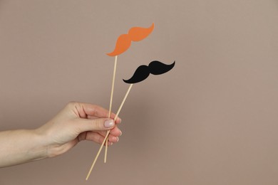 Photo of Woman with fake paper mustaches on beige background, closeup. Space for text
