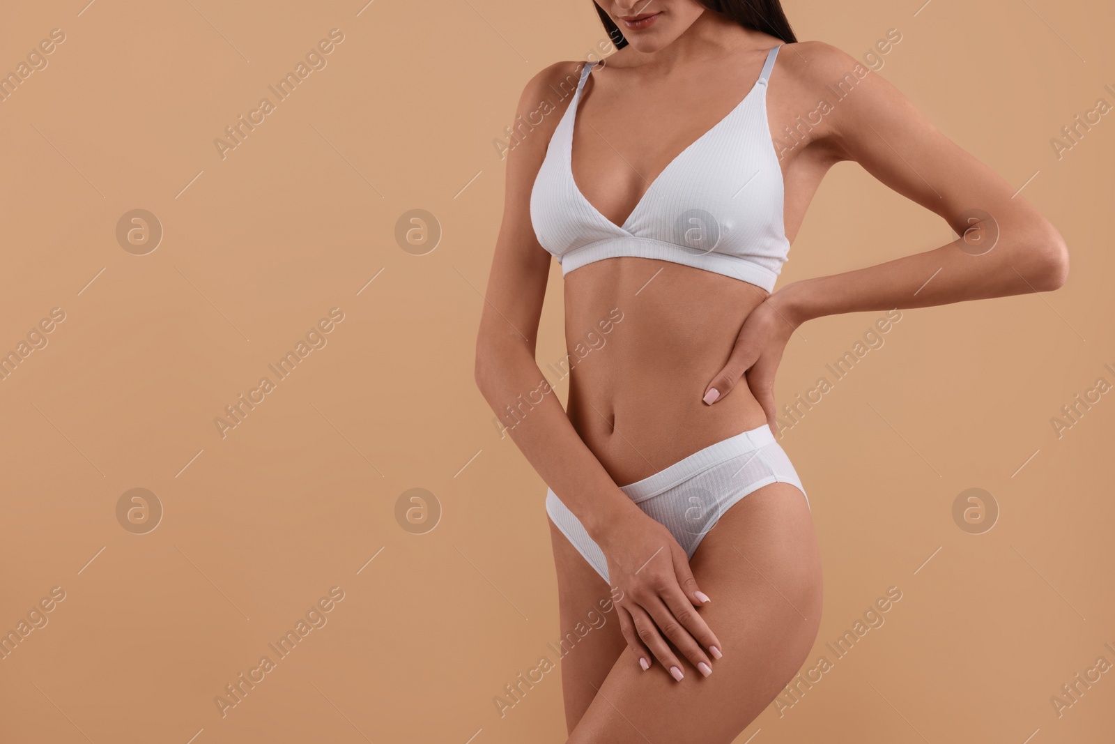 Photo of Young woman in stylish white bikini on beige background, closeup. Space for text