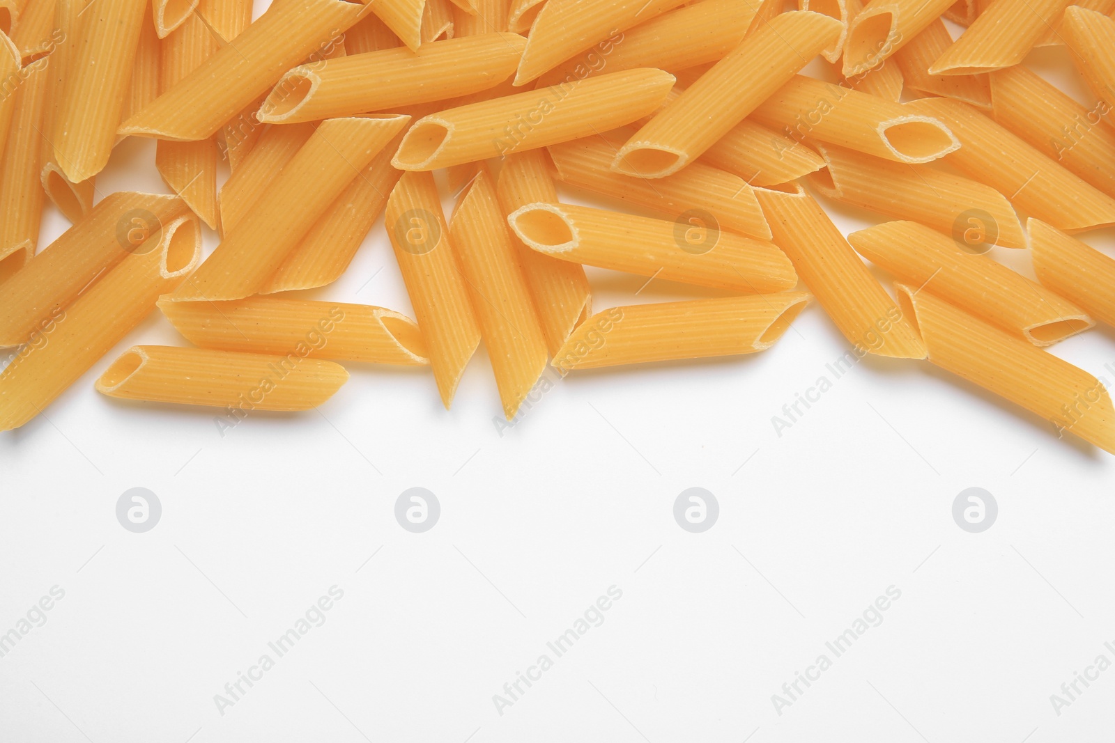 Photo of Raw penne pasta on white background, top view. Space for text