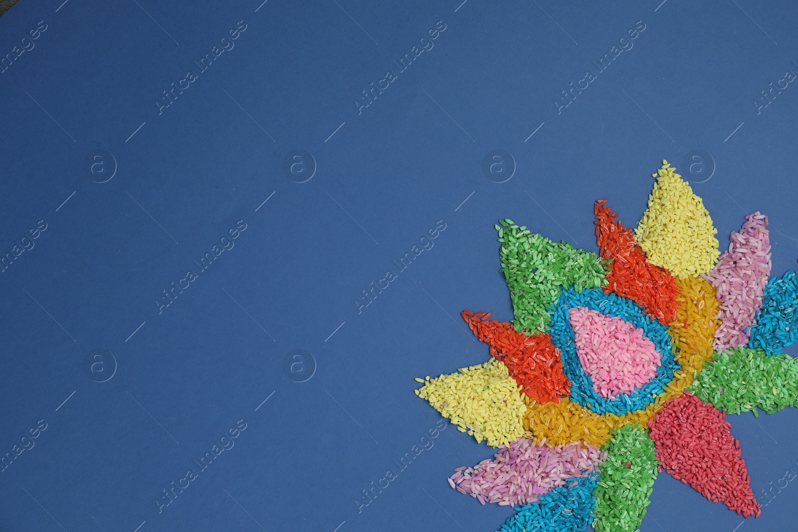 Photo of Diwali celebration. Colorful rangoli on blue background, top view. Space for text