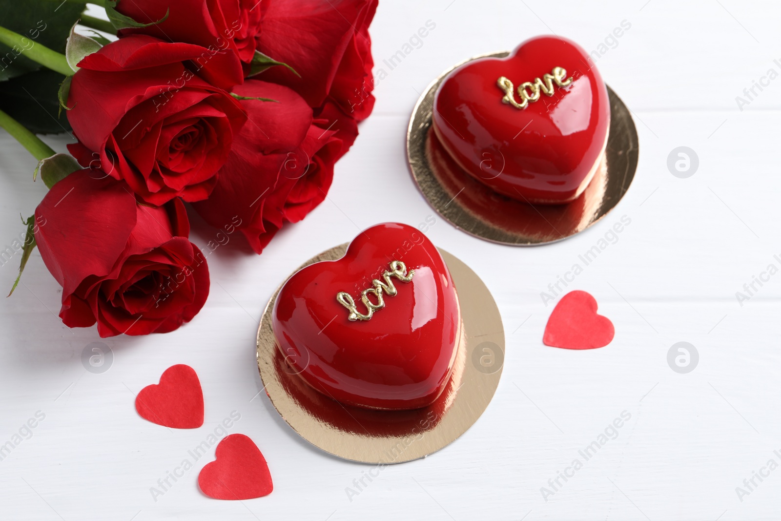 Photo of St. Valentine's Day. Delicious heart shaped cakes and beautiful roses on white wooden table, above view