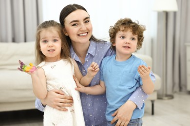 Photo of Mother and her little children with painted hands at home