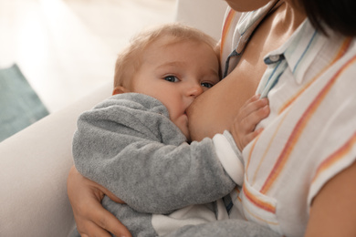 Photo of Woman breastfeeding her little baby at home, closeup
