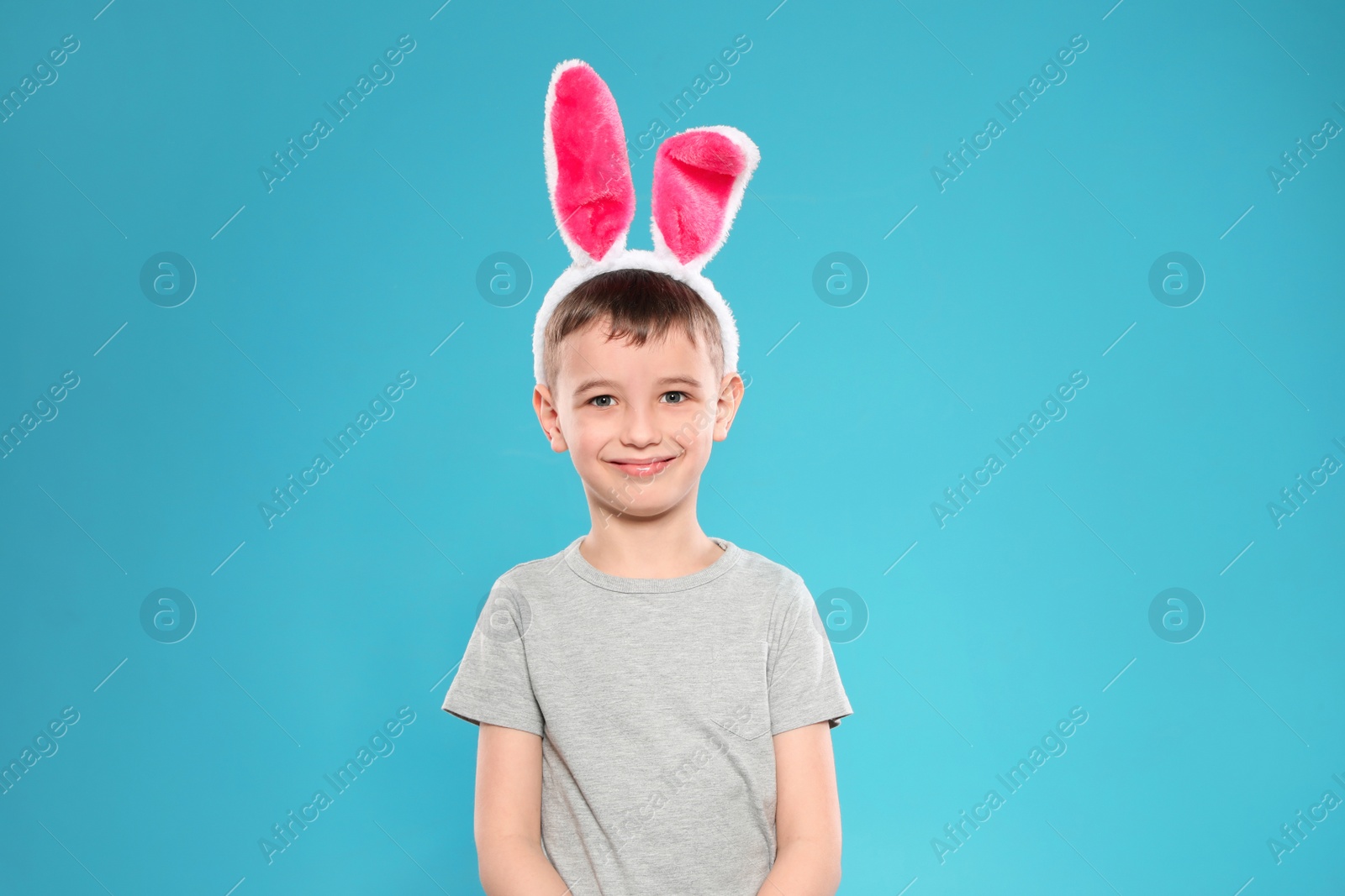 Photo of Portrait of little boy in Easter bunny ears headband on color background