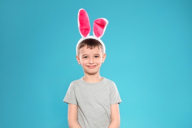 Photo of Portrait of little boy in Easter bunny ears headband on color background