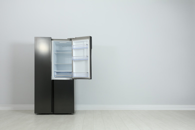 Photo of Modern refrigerator near light grey wall. space for text