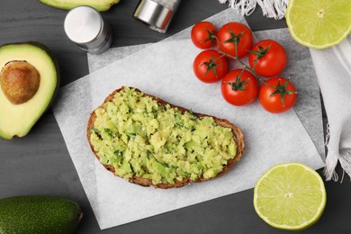 Photo of Delicious sandwich with guacamole, tomatoes and limes on gray wooden table, flat lay