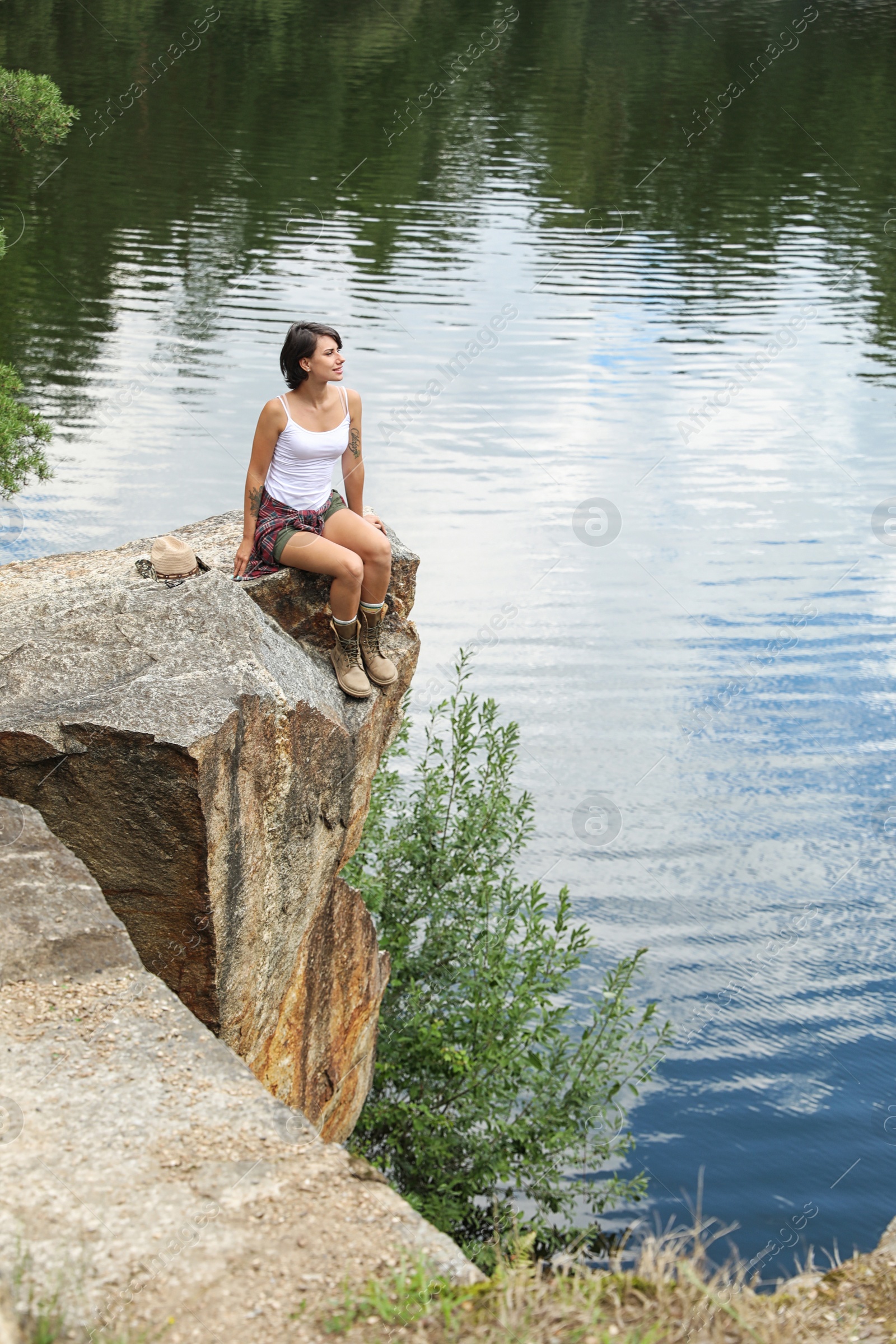 Photo of Young woman on rocky mountain near lake. Camping season