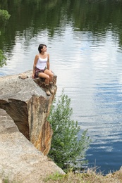 Photo of Young woman on rocky mountain near lake. Camping season