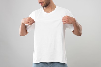 Man wearing white t-shirt on gray background, closeup