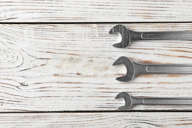 Photo of New wrenches on wooden background, top view with space for text. Plumber tools