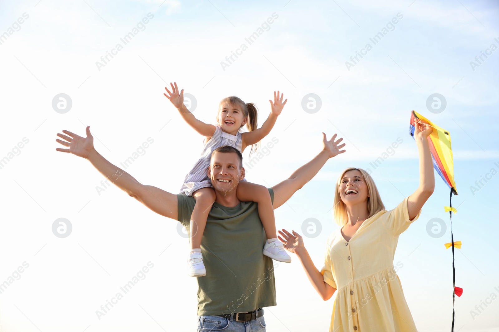 Photo of Happy parents with their child playing with kite on beach. Spending time in nature