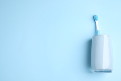 Toothbrush in holder on light blue background, top view. Space for text