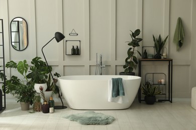 Photo of Stylish bathroom interior with modern tub and beautiful houseplants. Home design