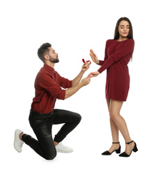 Photo of Young woman rejecting engagement ring from boyfriend on white background