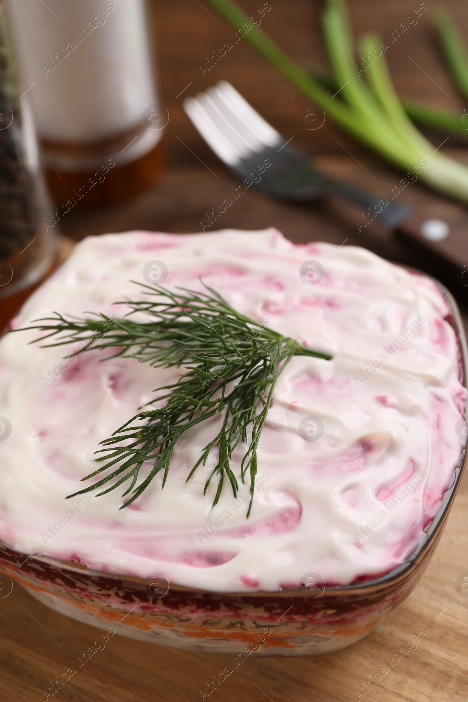 Photo of Herring under fur coat on wooden table, closeup. Traditional Russian salad