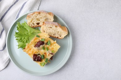 Photo of Tasty sausage casserole with green onion and bread on light grey table, top view. Space for text