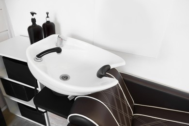 Photo of Modern wash unit with professional care products in barbershop, above view