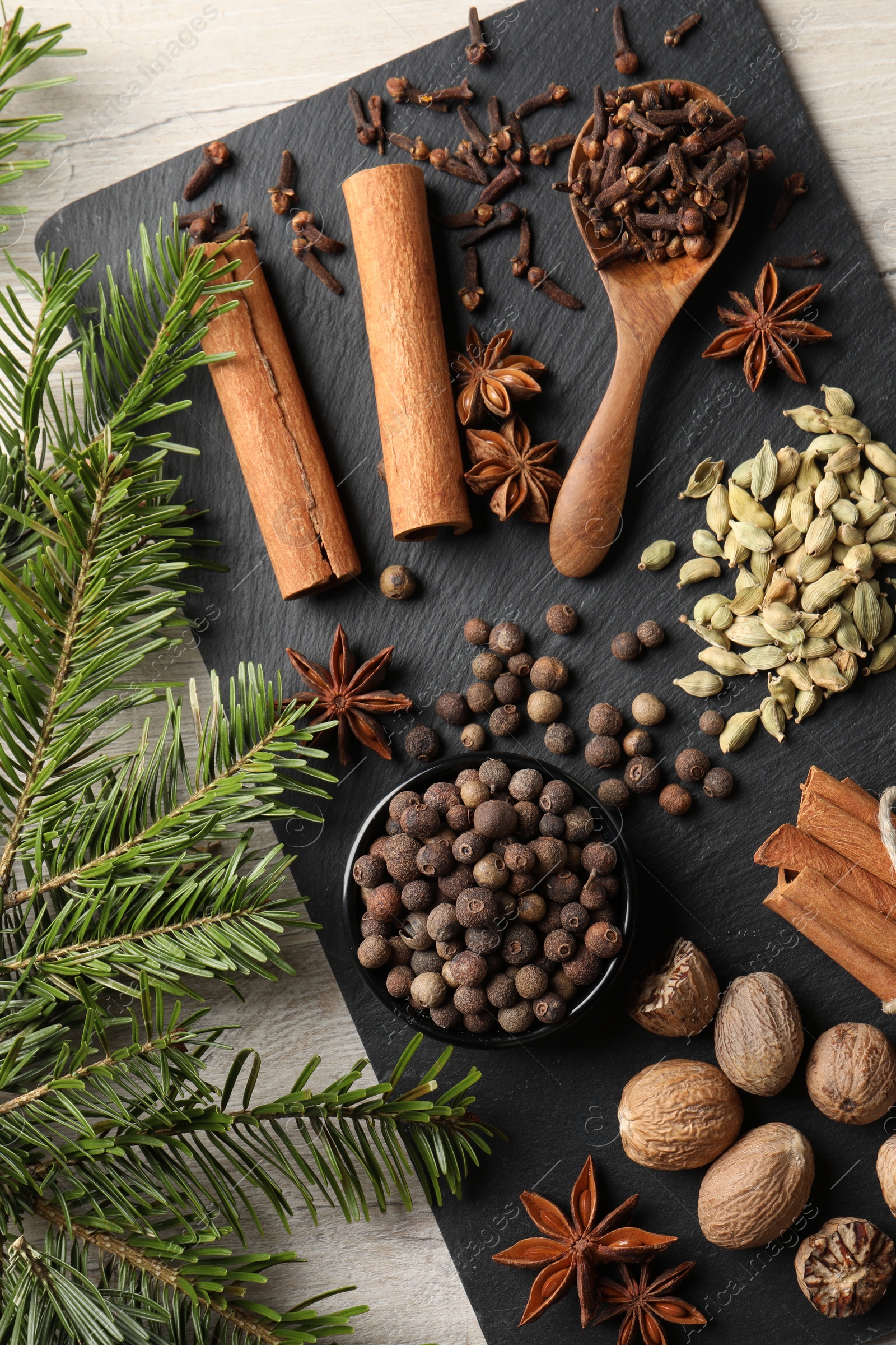 Photo of Different spices and fir branches on wooden table, flat lay