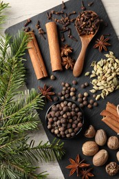 Different spices and fir branches on wooden table, flat lay