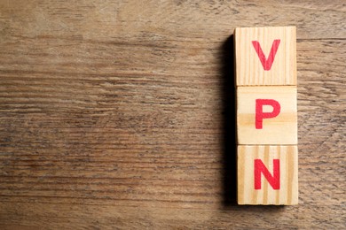 Photo of Cubes with acronym VPN on wooden table, top view. Space for text