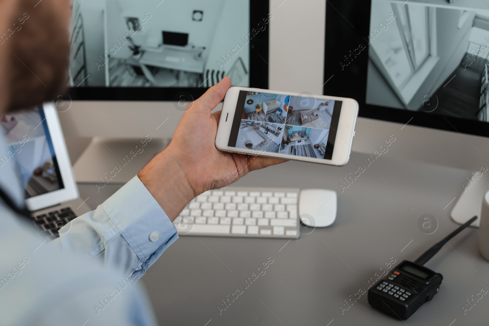 Photo of Male security guard monitoring home cameras using smartphone indoors, closeup