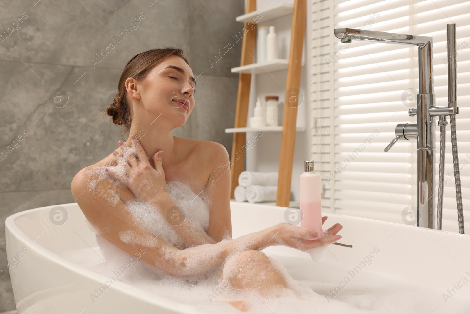 Photo of Woman taking bath with shower gel in bathroom