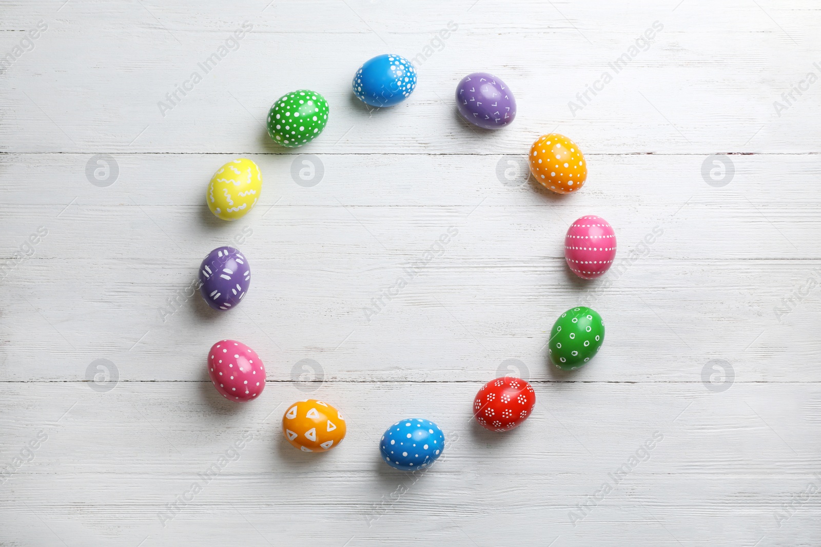 Photo of Decorated Easter eggs and space for text on wooden background, top view