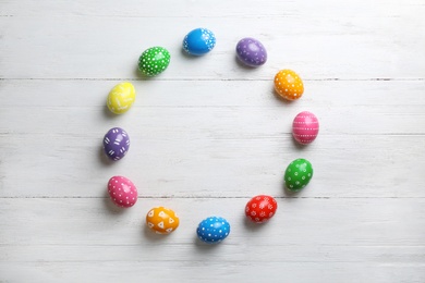 Photo of Decorated Easter eggs and space for text on wooden background, top view