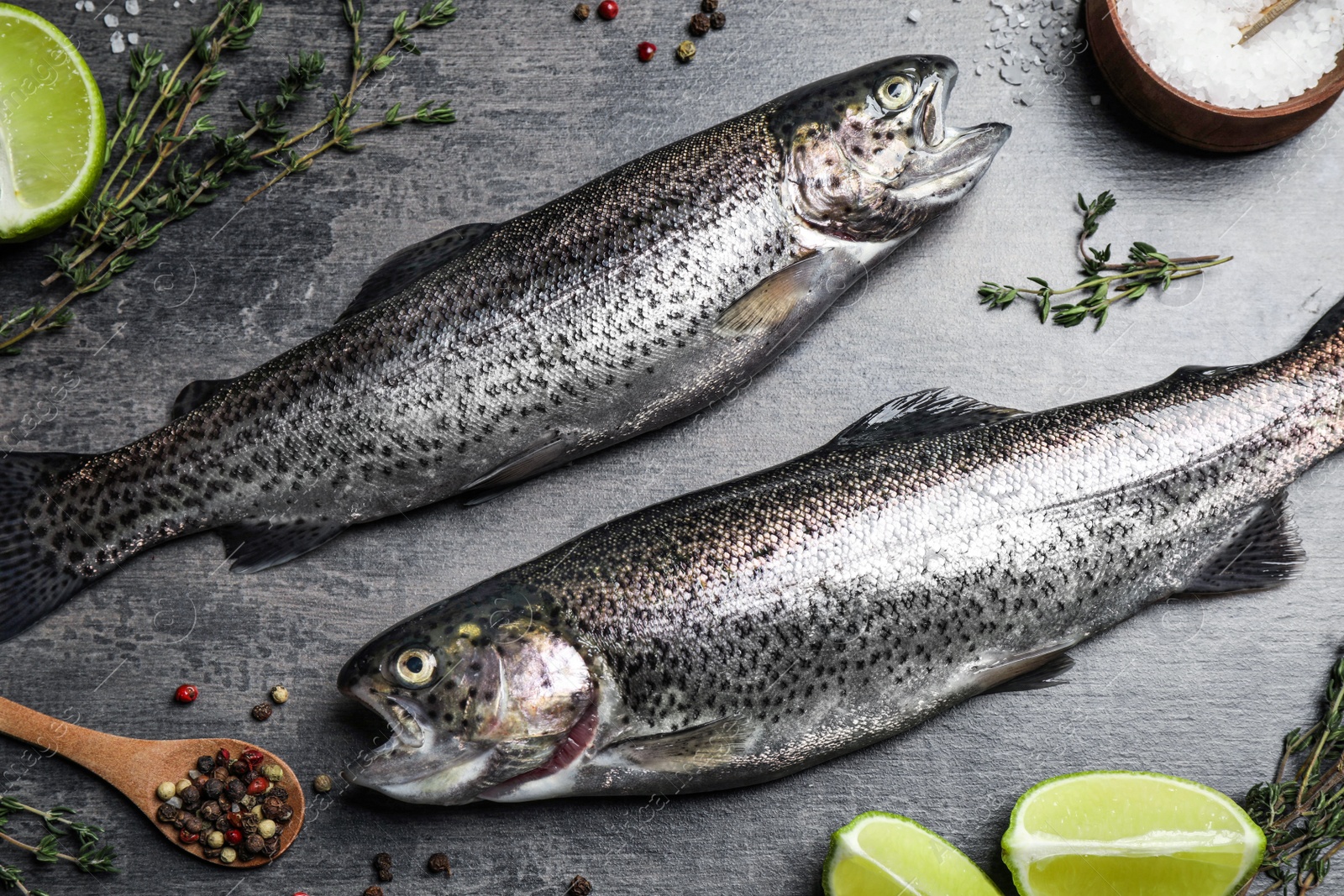 Photo of Raw cutthroat trout fish on grey table, flat lay