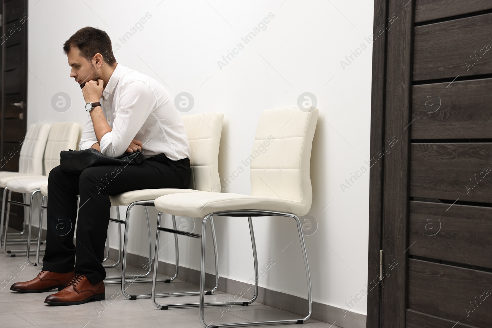 Photo of Man with briefcase waiting for job interview indoors