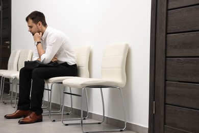 Man with briefcase waiting for job interview indoors