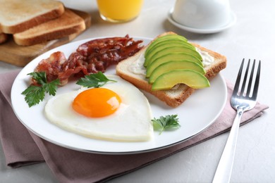 Photo of Romantic breakfast with fried bacon, heart shaped egg and avocado toast on light grey table, closeup. Valentine's day celebration