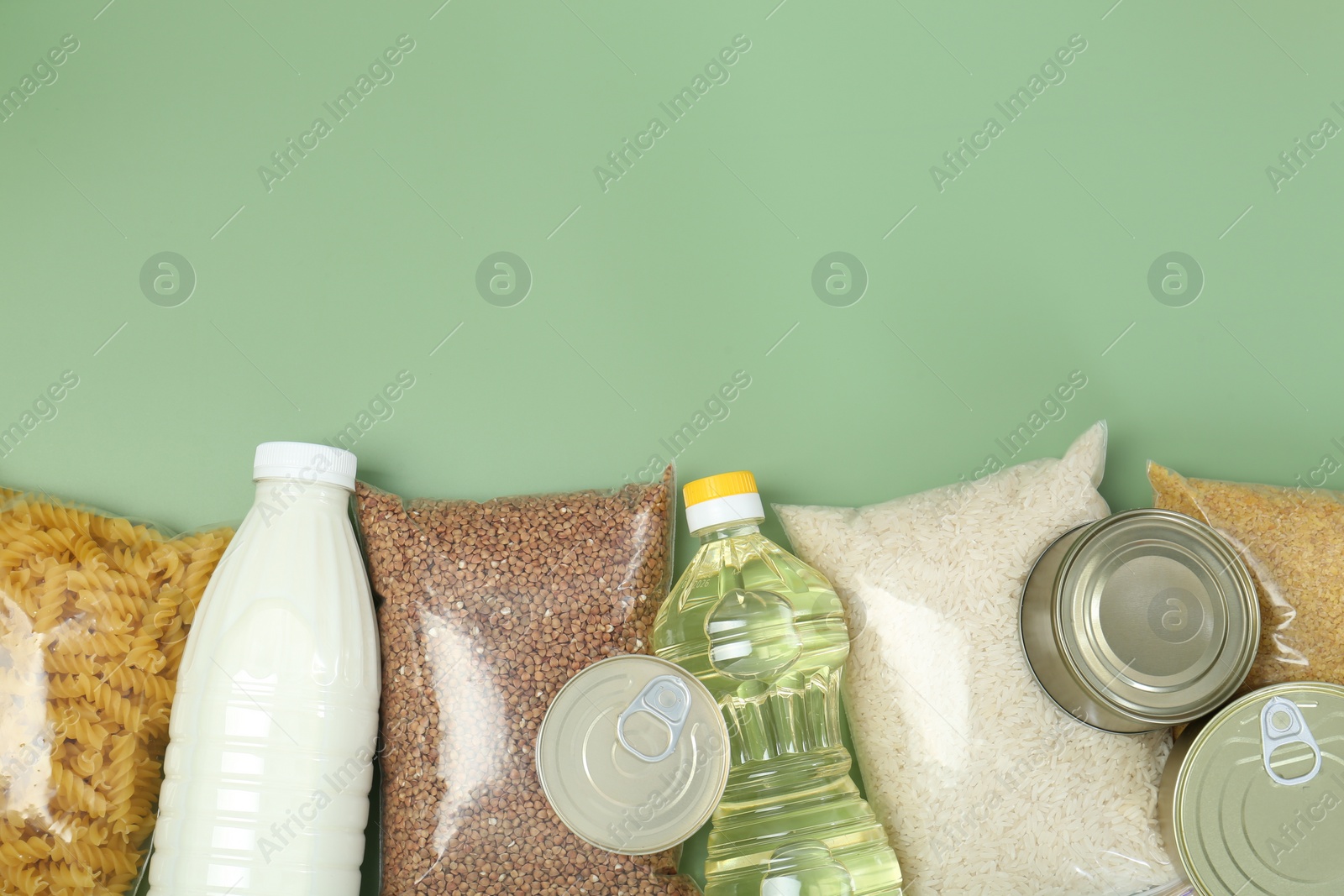 Photo of Humanitarian aid. Different food products for donation on green background, flat lay. Space for text